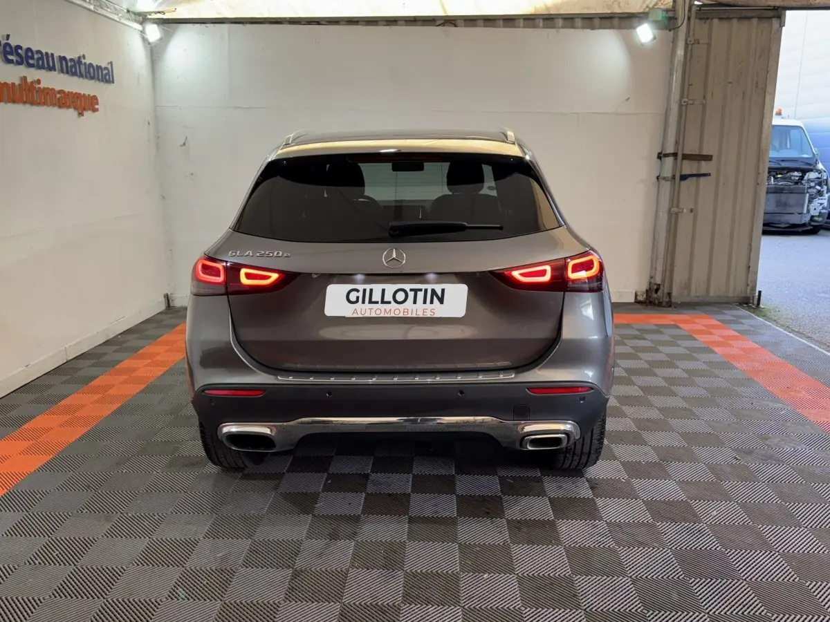 Vue arrière d'une Mercedes GLA 250 e Business Line gris foncé avec feux LED allumés dans un garage.