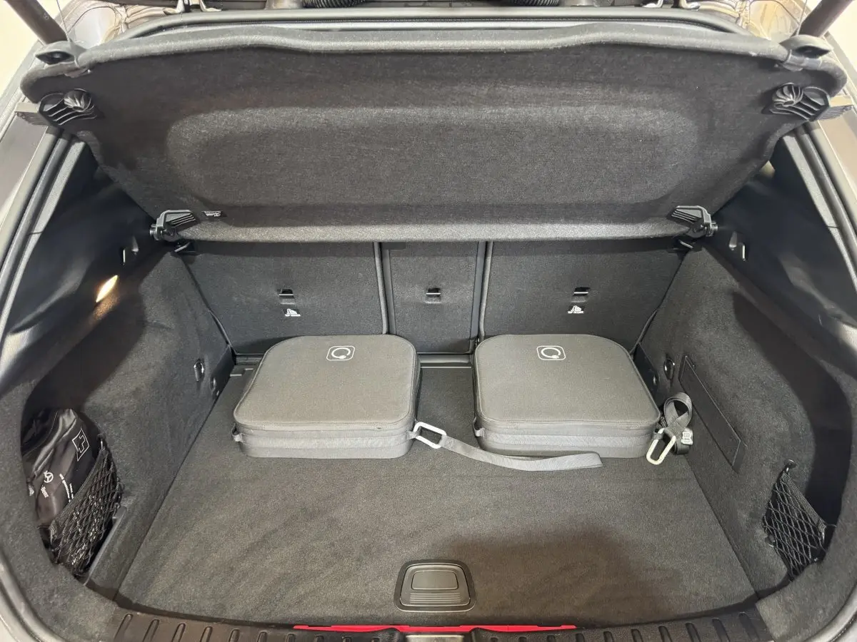 Vue plongeante sur le coffre ouvert gris foncé du Mercedes GLA 250 e Business Line avec deux sacs de rangement noirs.