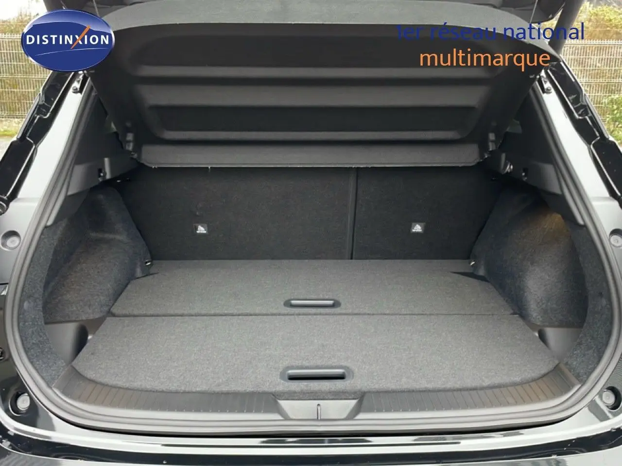 Coffre ouvert vu de l'arrière d'un Nissan Qashqai noir perle métal avec plancher de chargement plat et compartiments dissimulés.