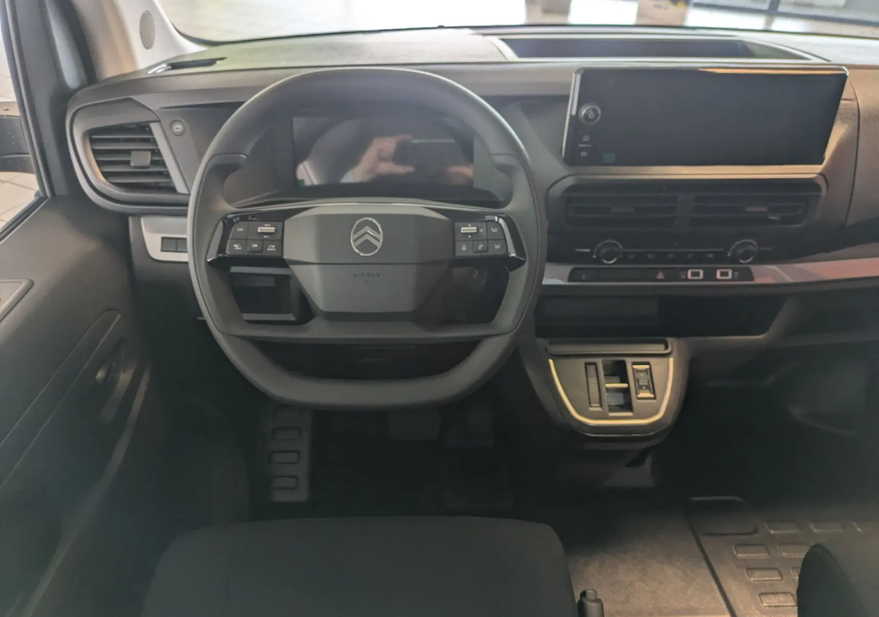 Vue intérieure frontale du tableau de bord noir du Citroën Jumpy Cabine Approfondie avec volant multifonction et écran tactile.