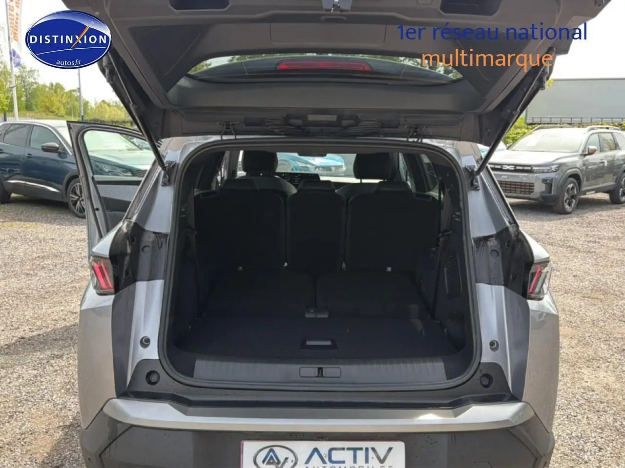 Vue arrière ouverte du Peugeot 5008 Hybrid 145 allure e-dcs6 gris artense, montrant le coffre spacieux et les sièges arrière.