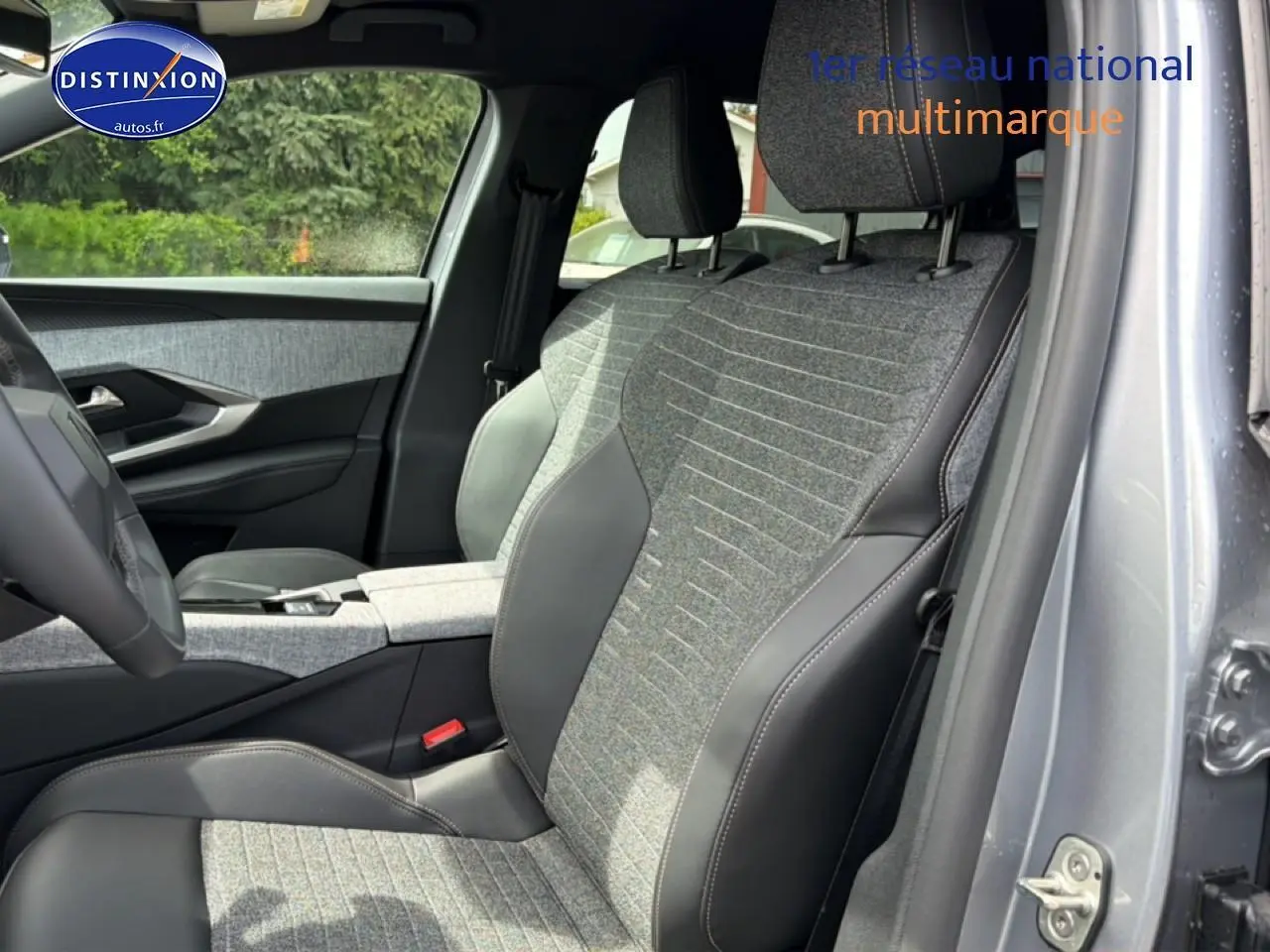 Vue intérieure côté conducteur du Peugeot 5008 gris Artense, sièges en tissu et cuir bicolore avec accoudoir central.