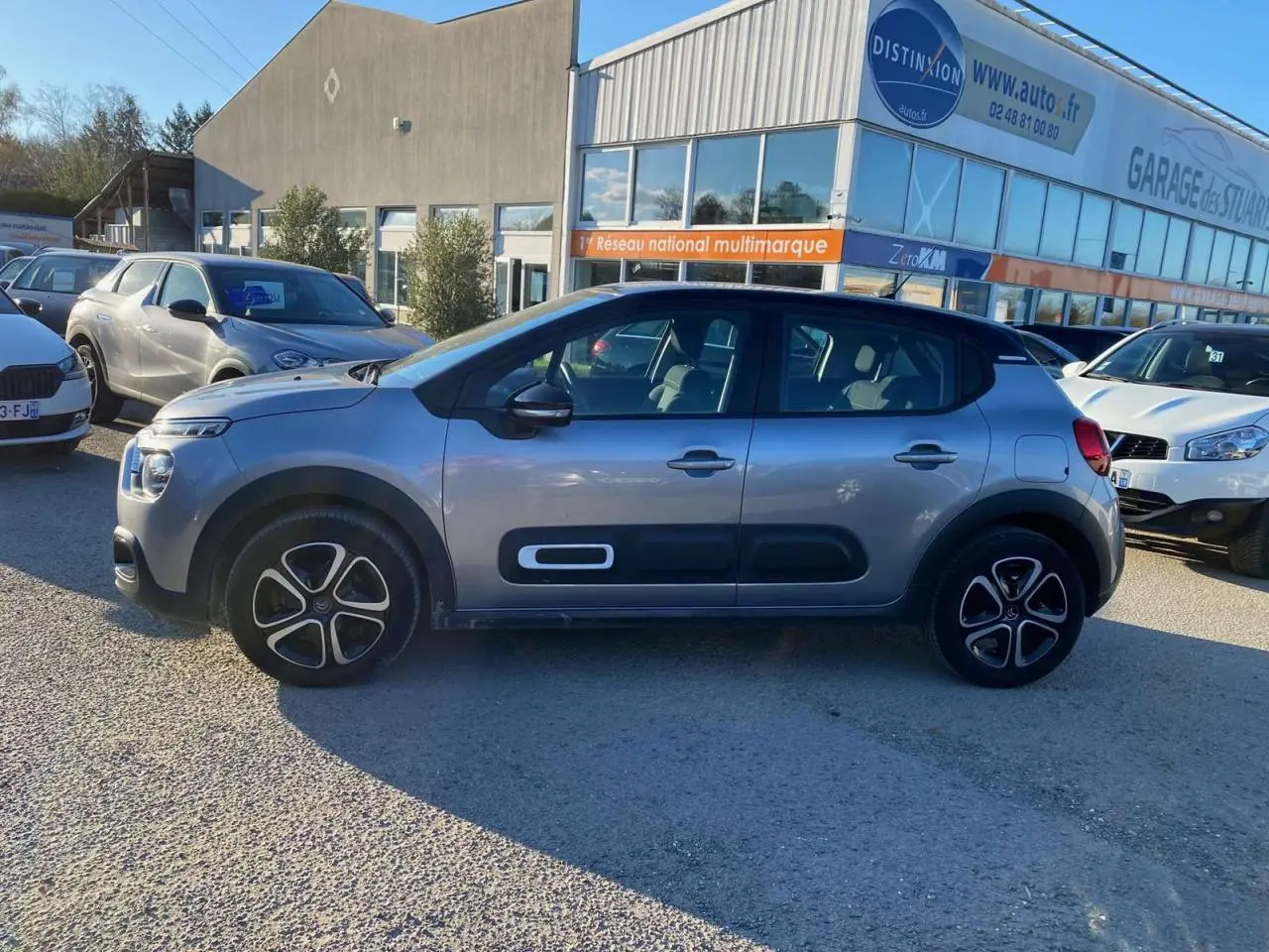 Profil latéral droit d'une Citroën C3 2022 gris Artense avec protections latérales noires et jantes alliage.
