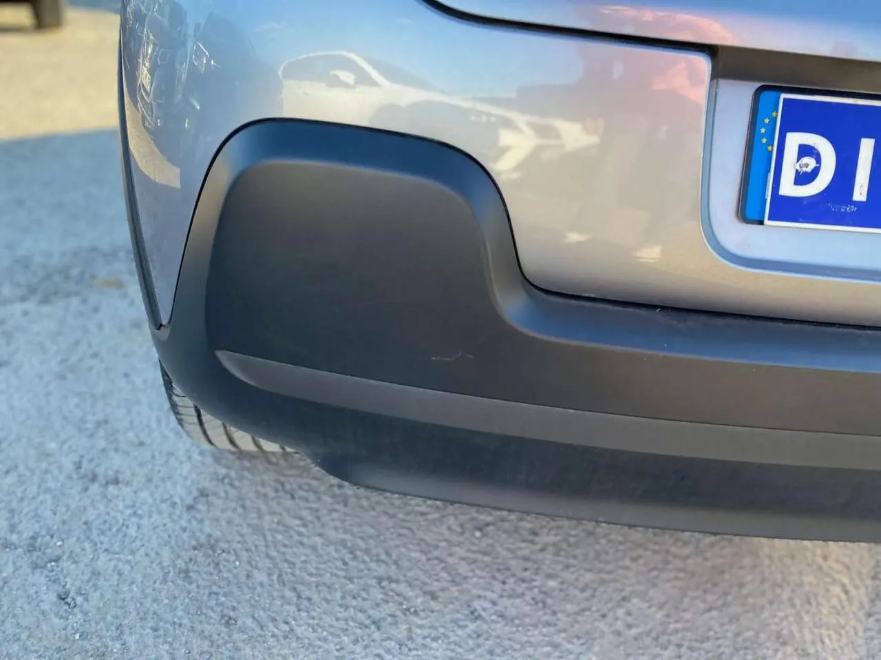 Gros plan sur le pare-chocs arrière gris Artense d'une Citroën C3 2022, avec partie inférieure noire et plaque d'immatriculation partielle.