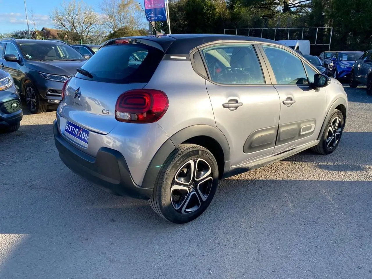 Vue 3/4 arrière droite d'une Citroën C3 gris Artense avec toit noir et jantes alliage distinctives.