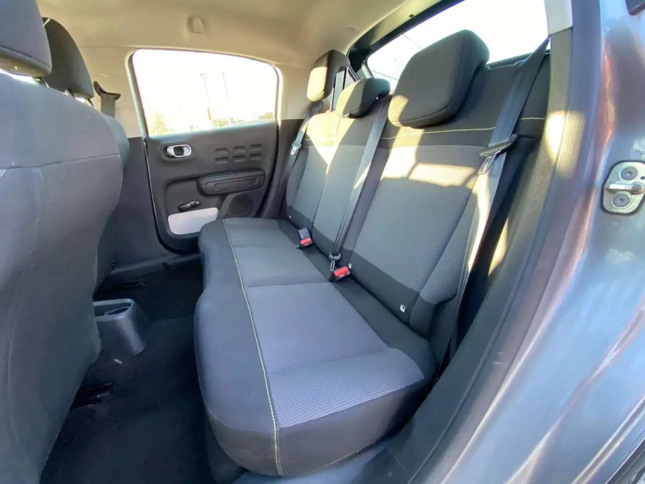 Vue intérieure de la banquette arrière grise de la Citroën C3 2022 côté droit avec ceintures et porte ouvert.