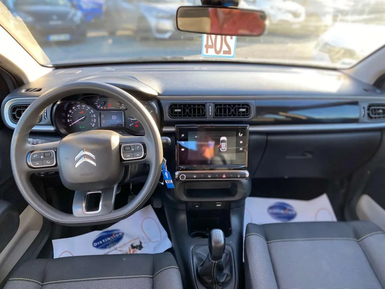 Vue intérieure avant du tableau de bord et volant de la Citroën C3 gris Artense avec écran tactile central et boîte manuelle.
