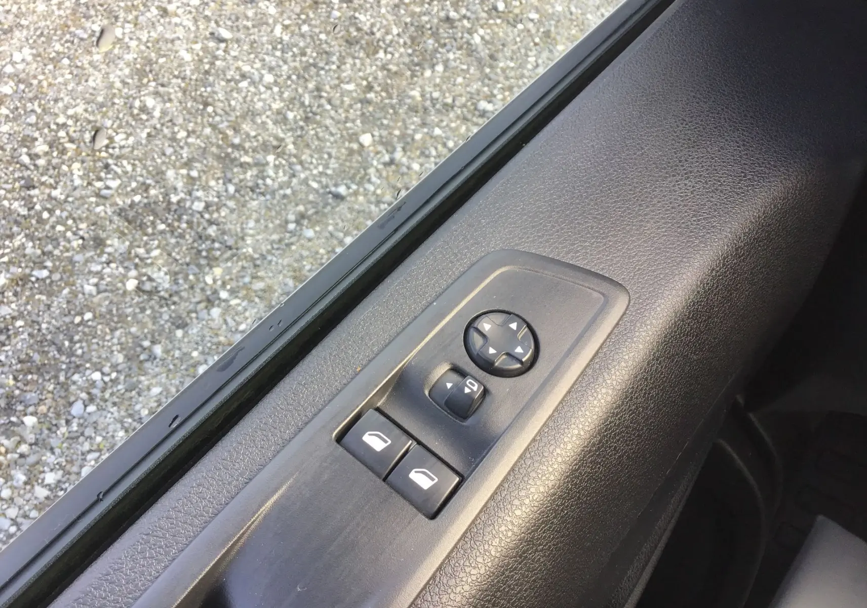 Gros plan sur les commandes de réglage des rétroviseurs et vitres côté conducteur d’un Fiat Scudo Fourgon blanc 2024.