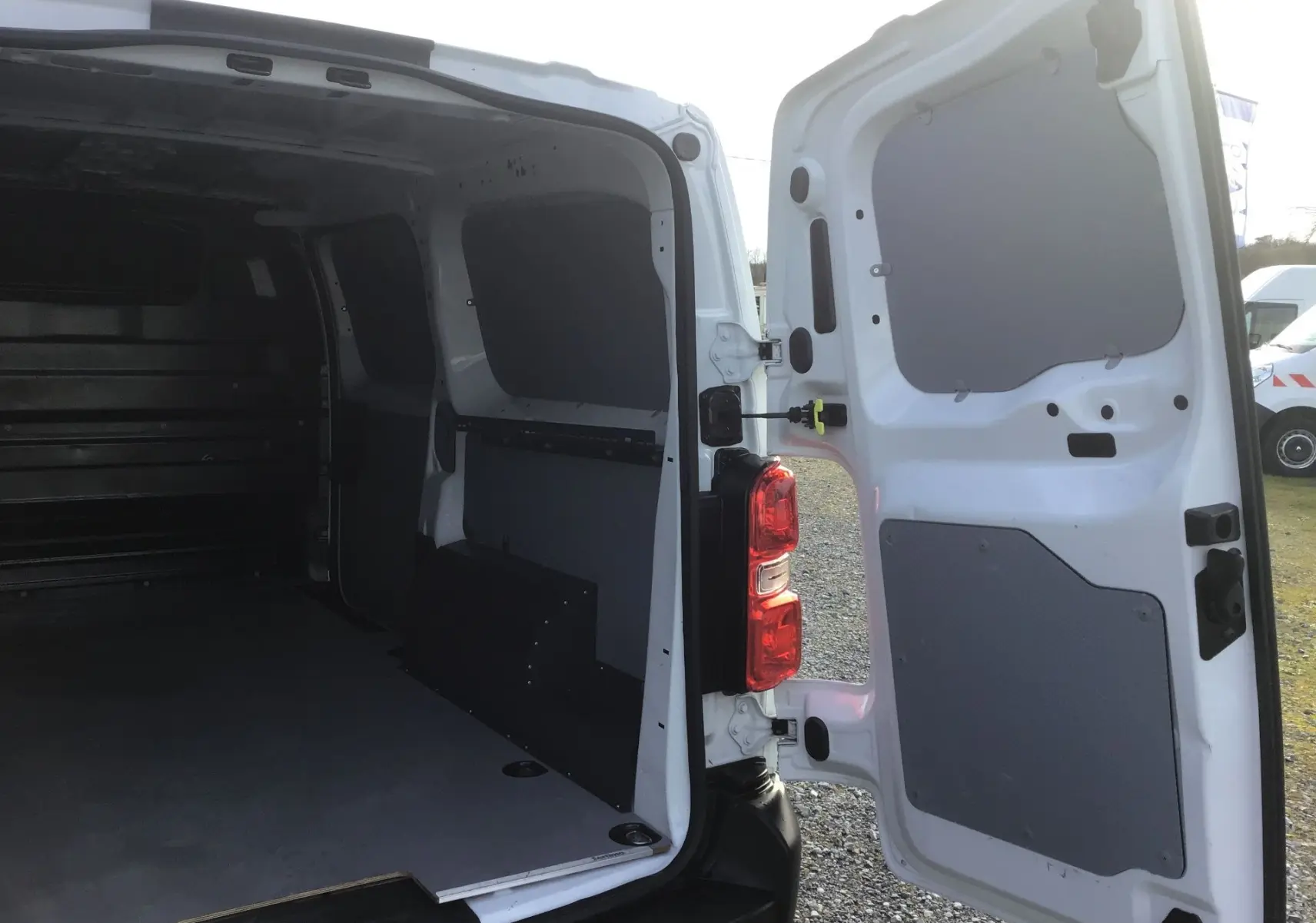 Vue arrière droite du fourgon blanc FIAT Scudo XL 2024 avec portes arrière ouvertes montrant l’espace de chargement vide.