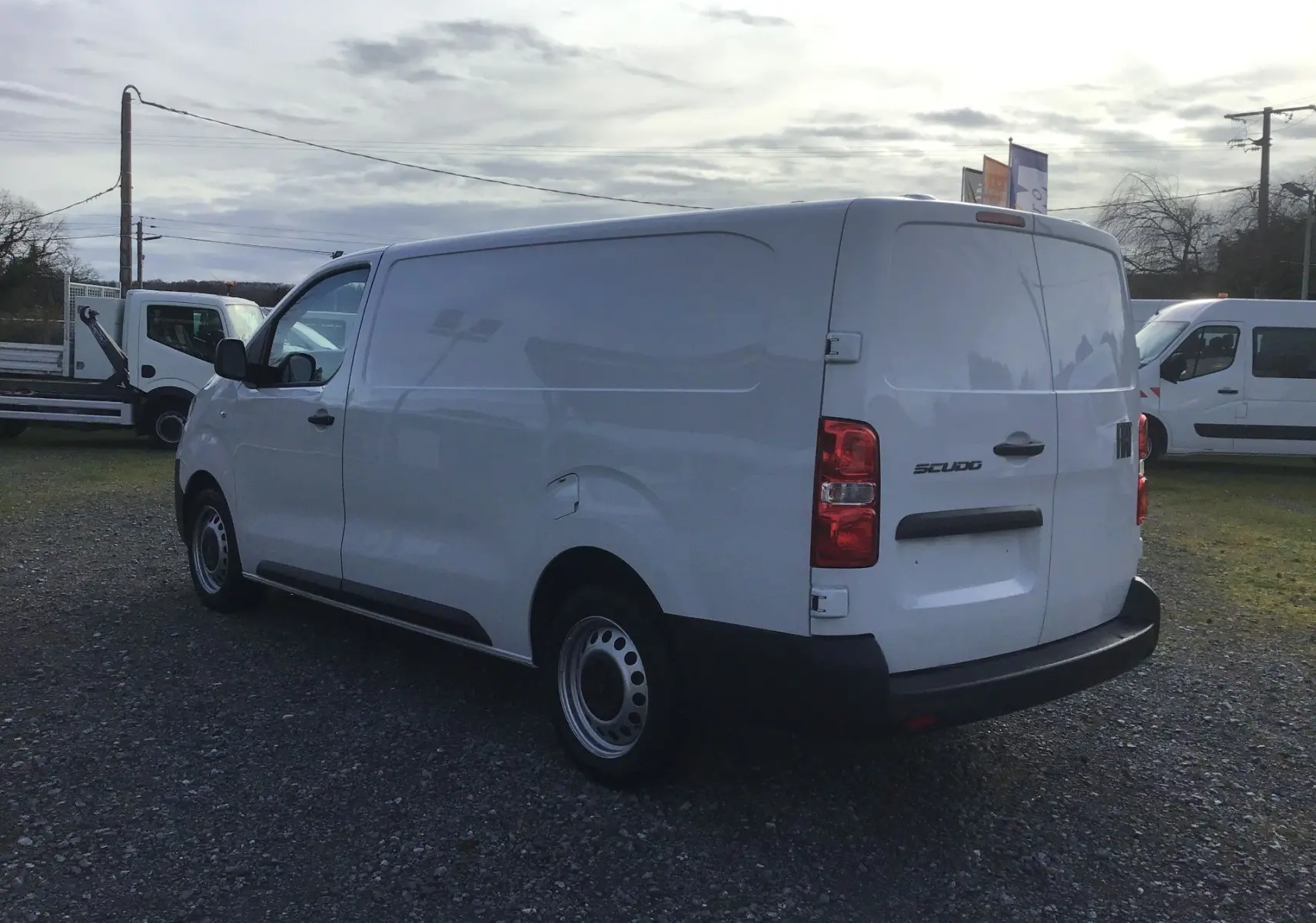 Fourgon FIAT Scudo XL blanc vu en 3/4 arrière droit, avec garde au sol rehaussée et plaque de protection visible.