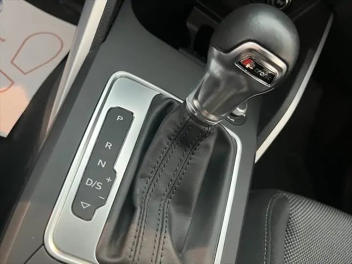 Le levier de vitesses automatique S-Tronic en cuir noir de l'Audi Q2 35 TFSI, vue rapprochée de la console centrale.