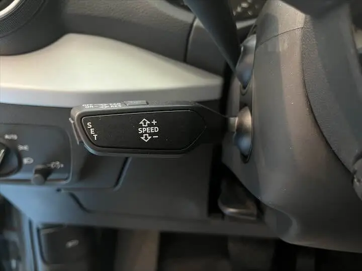 Gros plan sur la console centrale noire de l'Audi Q2 35 TFSI avec molette de commande multimédia et boutons fonctionnels.