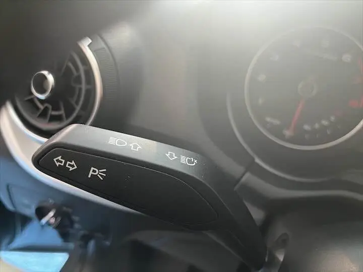 Gros plan sur la commande des clignotants et feux du tableau de bord d'un Audi Q2 gris Daytona 2020.