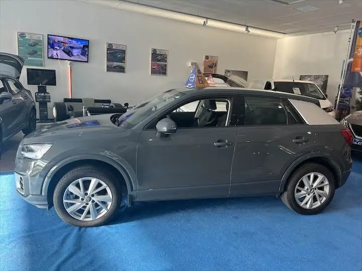 Audi Q2 35 TFSI gris Daytona métal vue de profil côté gauche en intérieur avec toit contrasté blanc.
