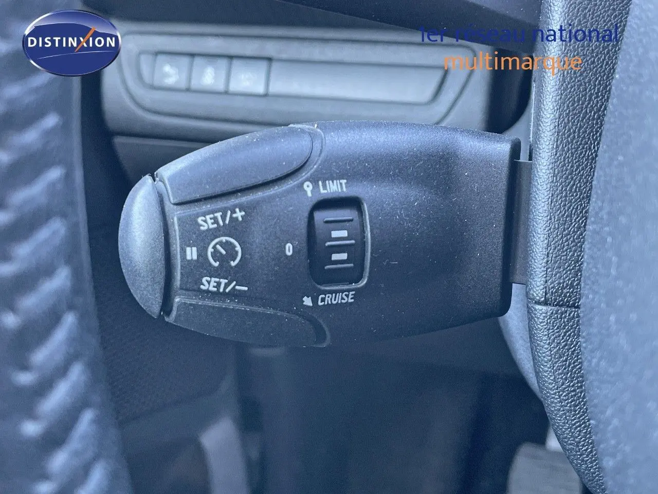 Gros plan sur la commande de régulateur et limiteur de vitesse du Peugeot 2008 blanc de 2017, intérieur côté gauche.