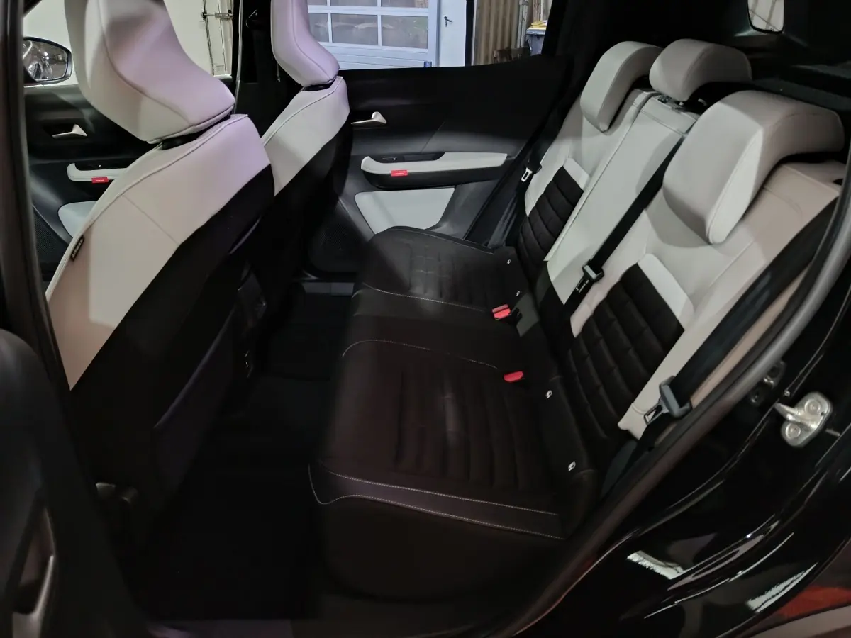 Vue intérieure arrière côté droit de la Citroën C3 hybride 2025, sièges bicolores noir et beige avec ceinture de sécurité.