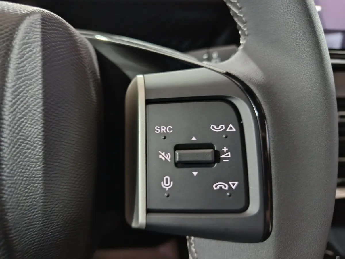 Gros plan sur les commandes multifonctions du volant cuir noir de la Citroën C3 hybride 2025.