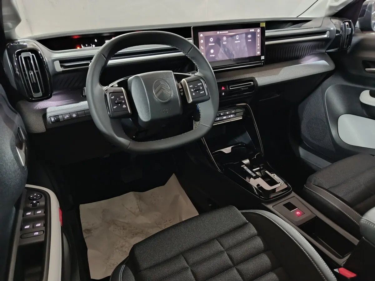 Intérieur de la Citroën C3 Hybride 2025 en noir, vue côté conducteur sur le volant cuir et écran tactile central.