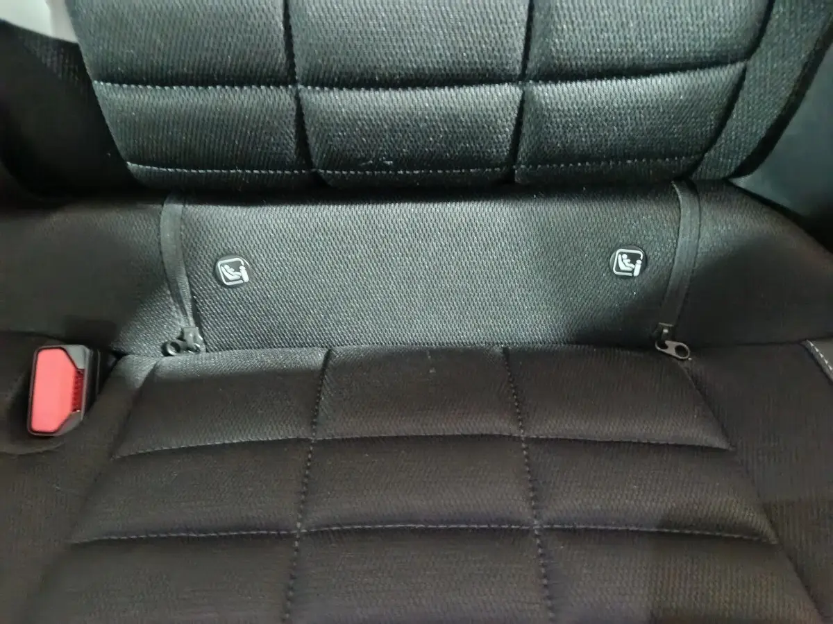 Gros plan sur la banquette arrière noire de la Citroën C3 hybride 2025 avec fixation Isofix et boucle de ceinture rouge visible.