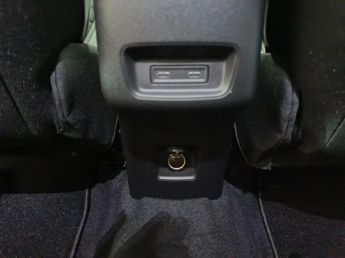 Prise USB et prise 12V vue en gros plan à l'arrière de la console centrale d'une Citroën C3 noire hybride.