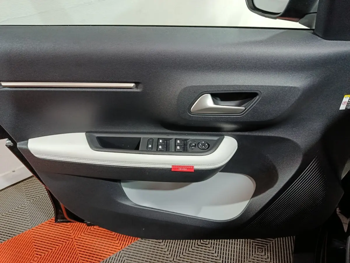 Vue rapprochée de la porte avant gauche noire de la Citroën C3 hybride 2025 avec garniture grise et commandes électriques.