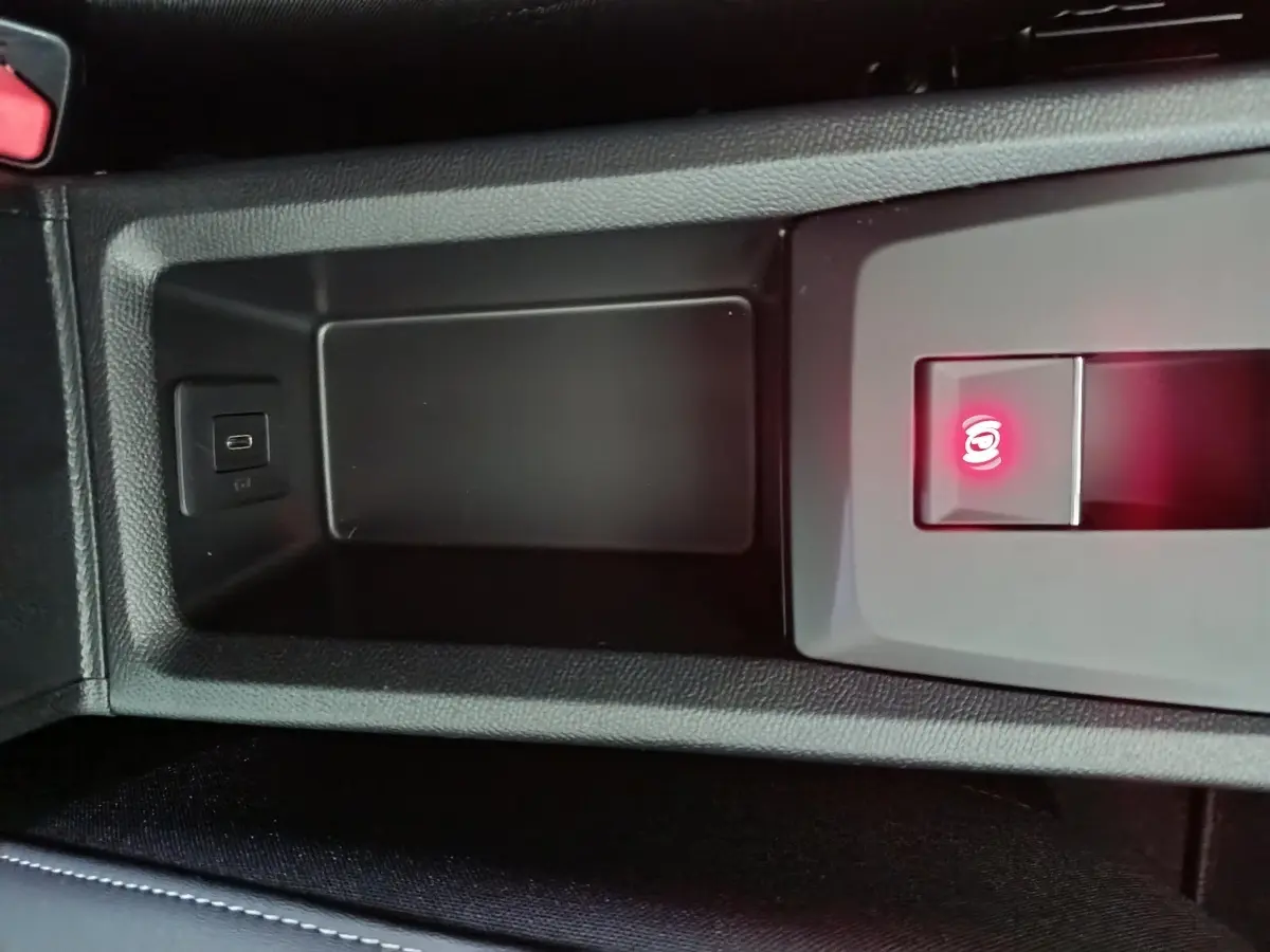 Gros plan sur la console centrale noire de la Citroën C3 hybride 2025 avec frein à main électrique et port USB visible.