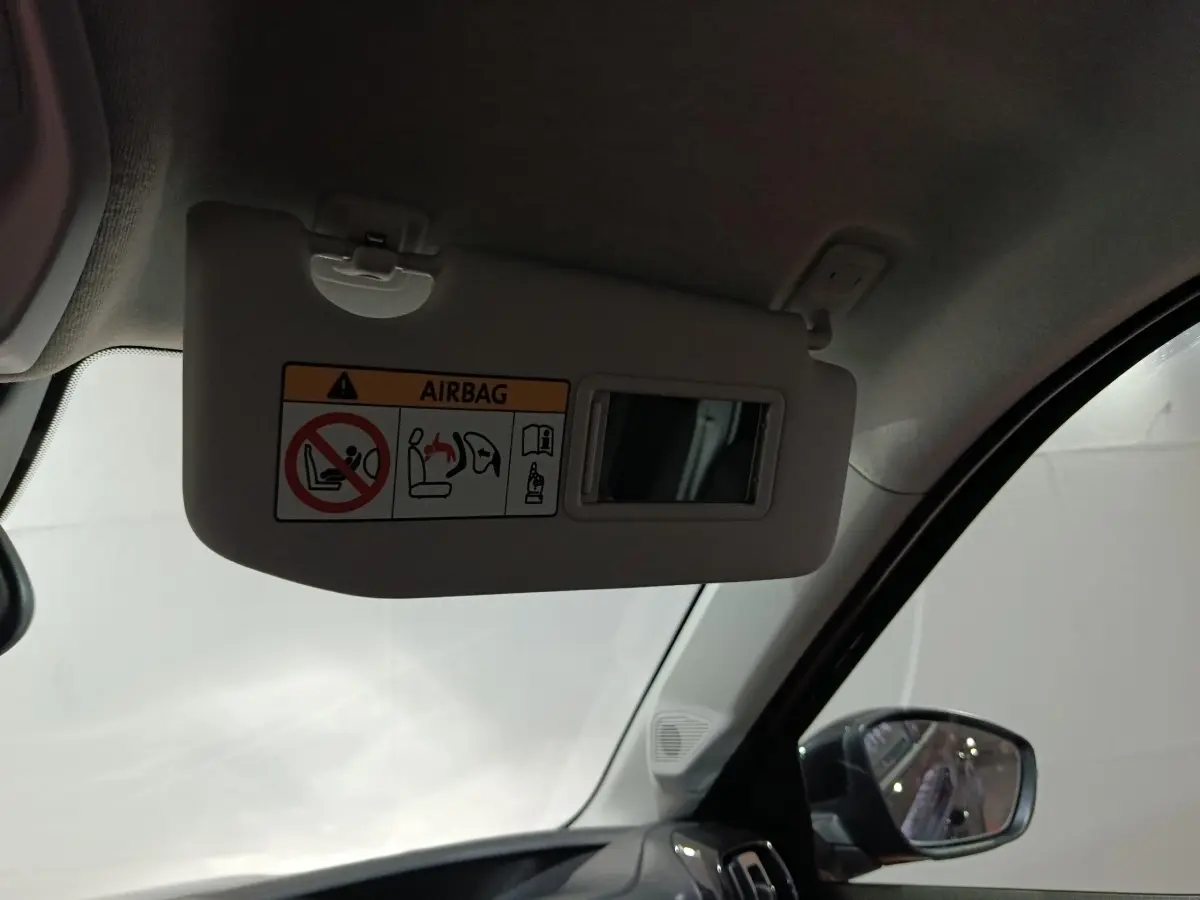 Vue intérieure côté conducteur sur le pare-soleil beige avec miroir et rétroviseur extérieur noir d'une Citroën C3 hybride 2025.