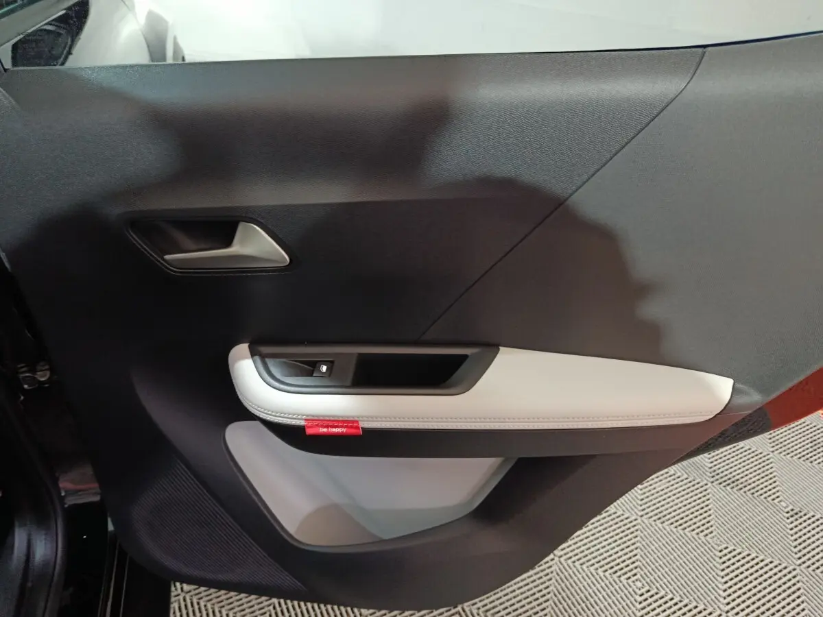 Vue intérieure du panneau de porte côté gauche de la Citroën C3 hybride 2025, avec accoudoir clair et bouton de fenêtre.
