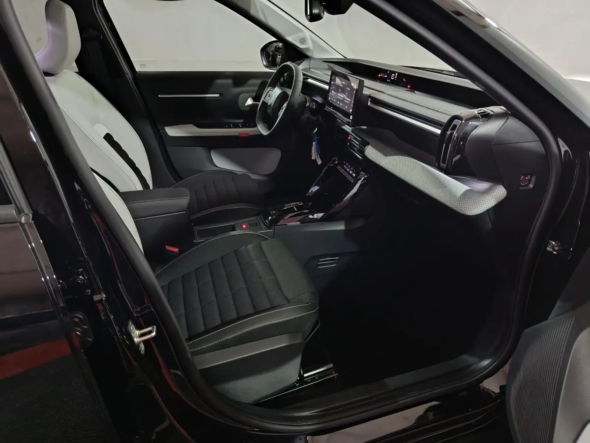 Intérieur avant droit de la Citroën C3 hybride noire 2025 avec sièges bicolores et écran tactile central.