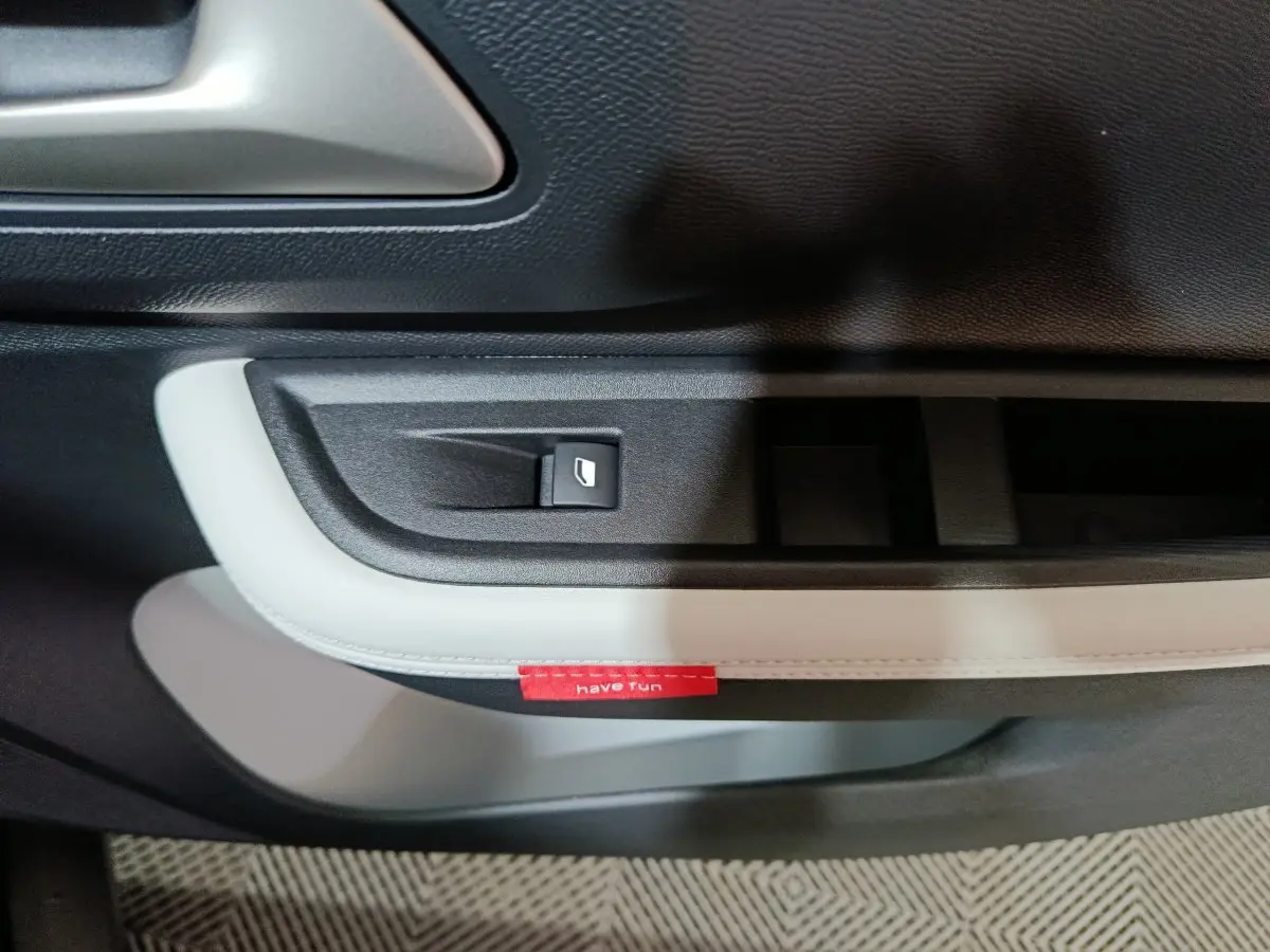 Détail de la poignée de porte intérieure côté gauche de la Citroën C3 hybride noire avec bouton de commande de vitre et étiquette rouge "have fun".