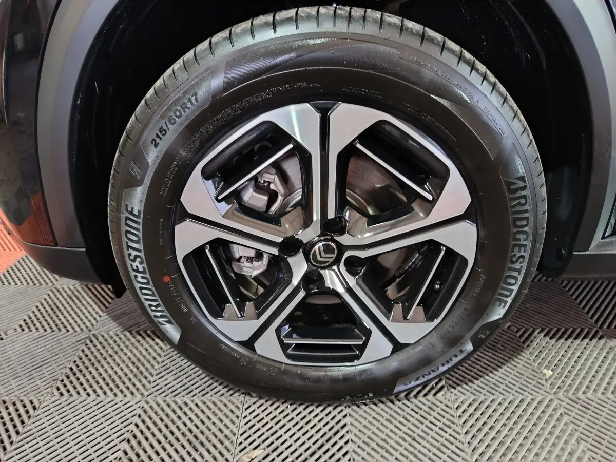 Gros plan sur la roue avant droite d'une Citroën C3 noire, mettant en valeur le pneu Bridgestone et l'aile du véhicule.