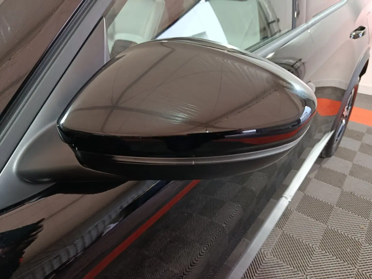 Gros plan sur le rétroviseur droit noir brillant de la Citroën C3 hybride 2025, avec clignotant intégré.