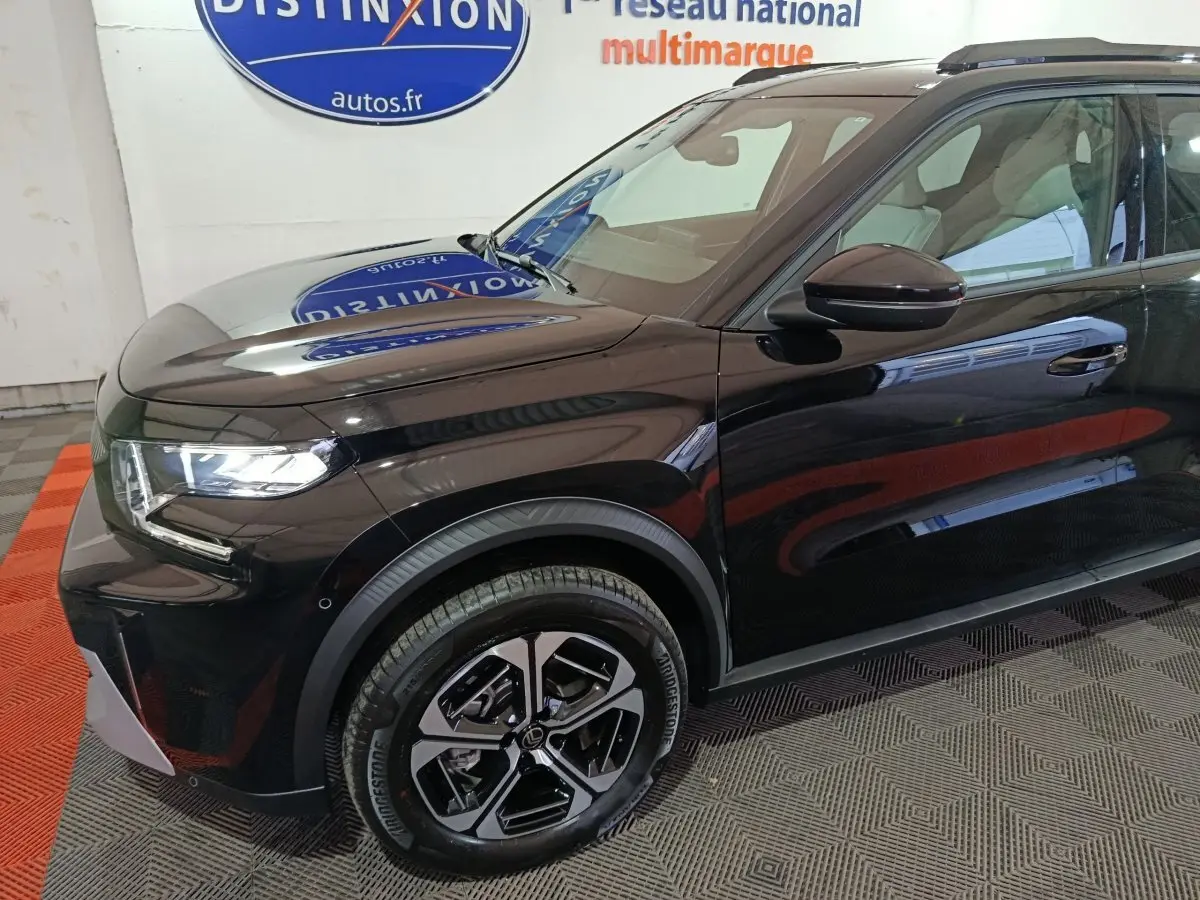 Vue 3/4 avant gauche d'une Citroën C3 hybride noire, avec jantes modernes et phares LED allumés.