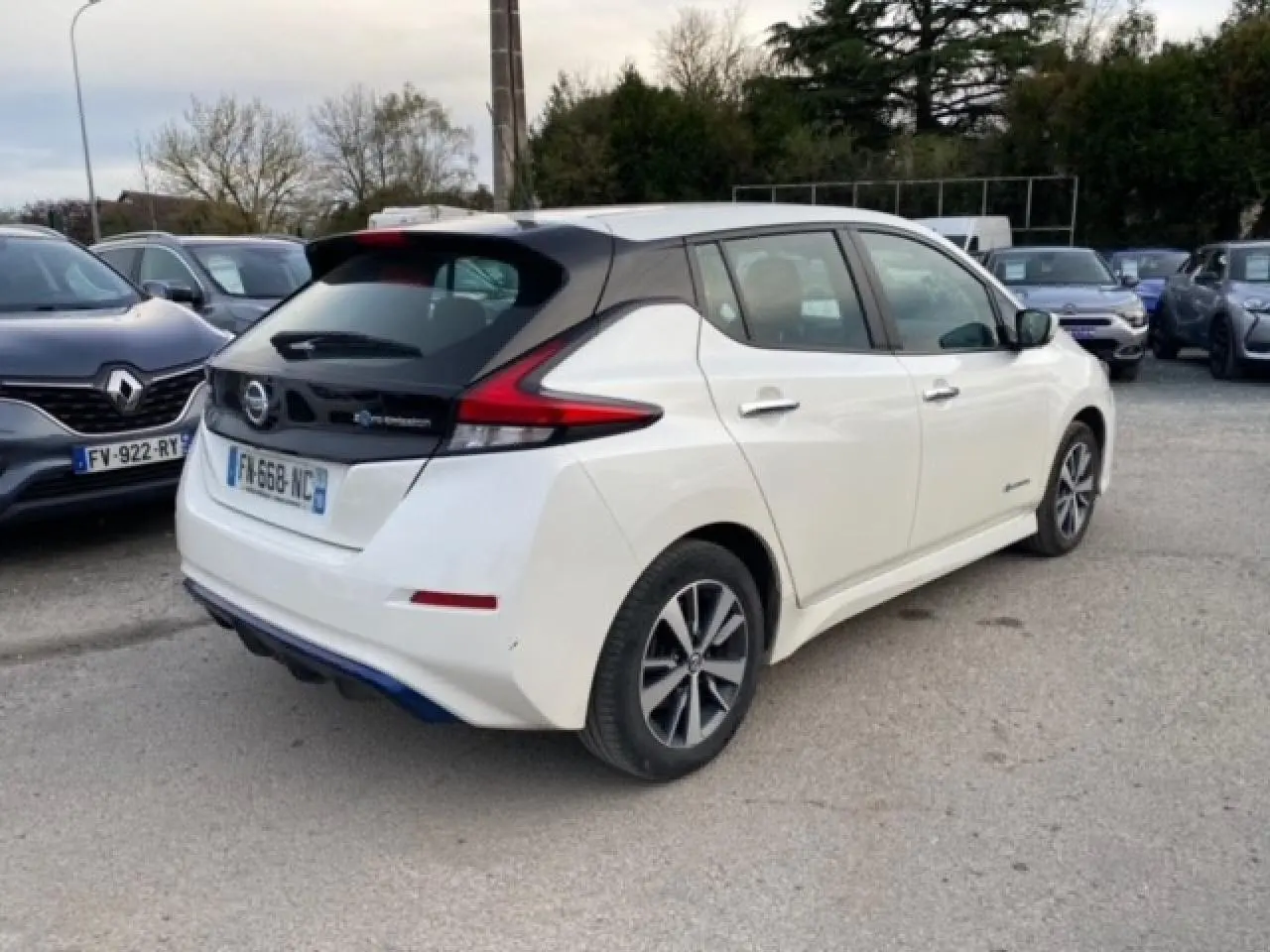 Vue 3/4 arrière droite d'une Nissan Leaf 40 kWh blanche avec toit noir et feux arrière LED distinctifs.
