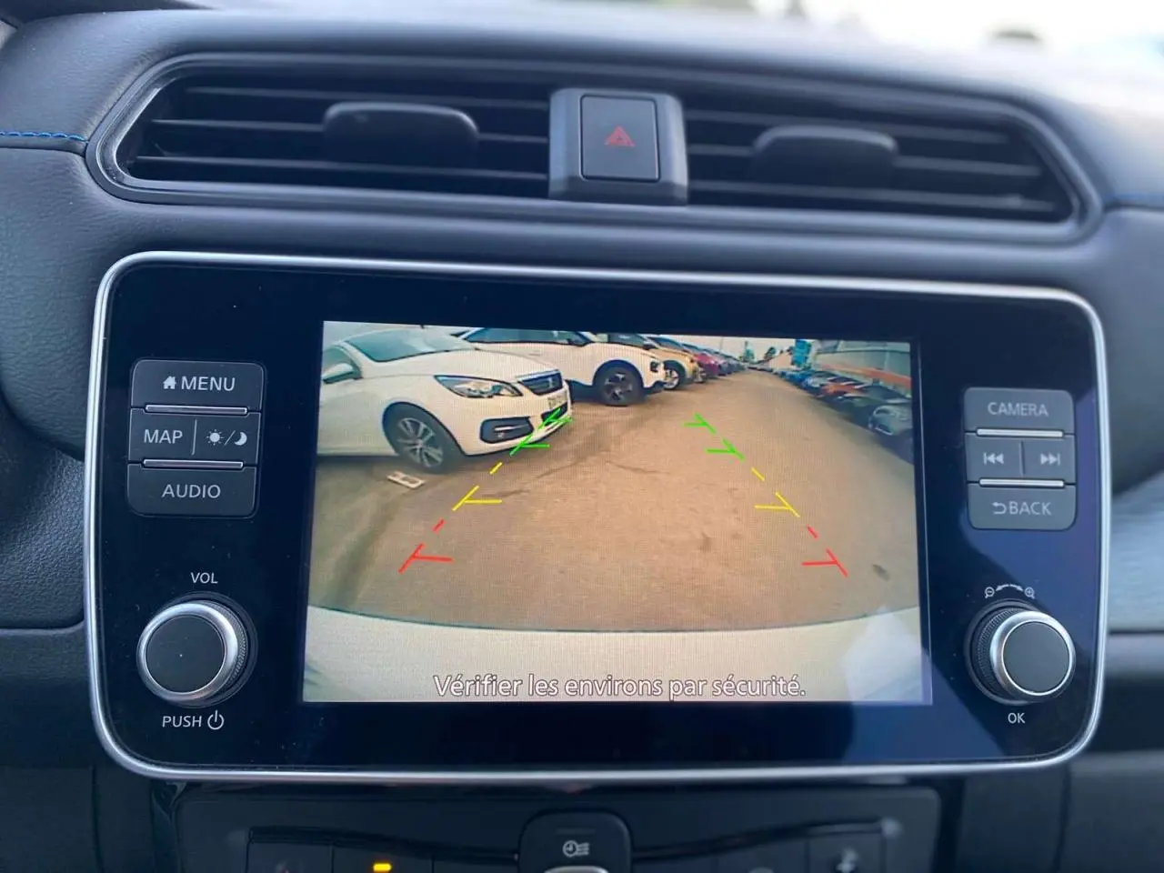 Écran tactile central montrant la caméra de recul avec guidage coloré, intérieur noir du Nissan Leaf blanc 2020.
