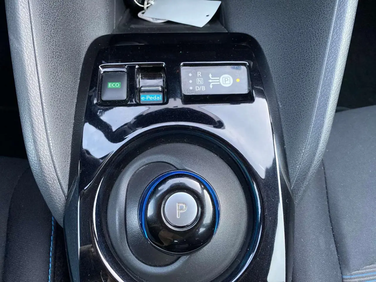 Vue rapprochée de la console centrale noire du Nissan Leaf blanc, avec sélecteur de vitesse circulaire et bouton e-Pedal.