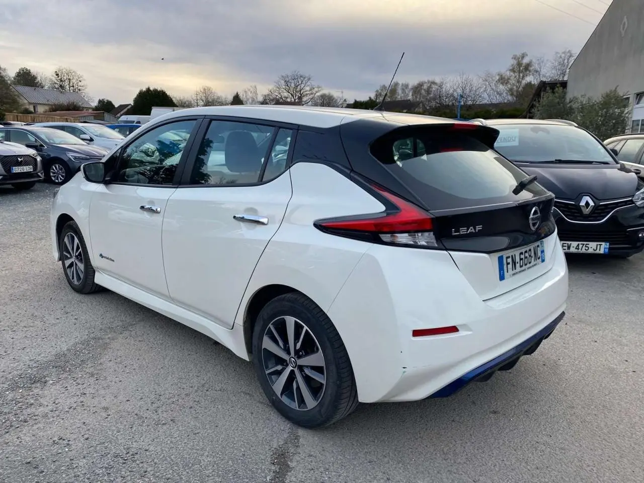Vue 3/4 arrière droite d'une Nissan Leaf blanche 2020 avec toit noir et feux arrière LED distinctifs.