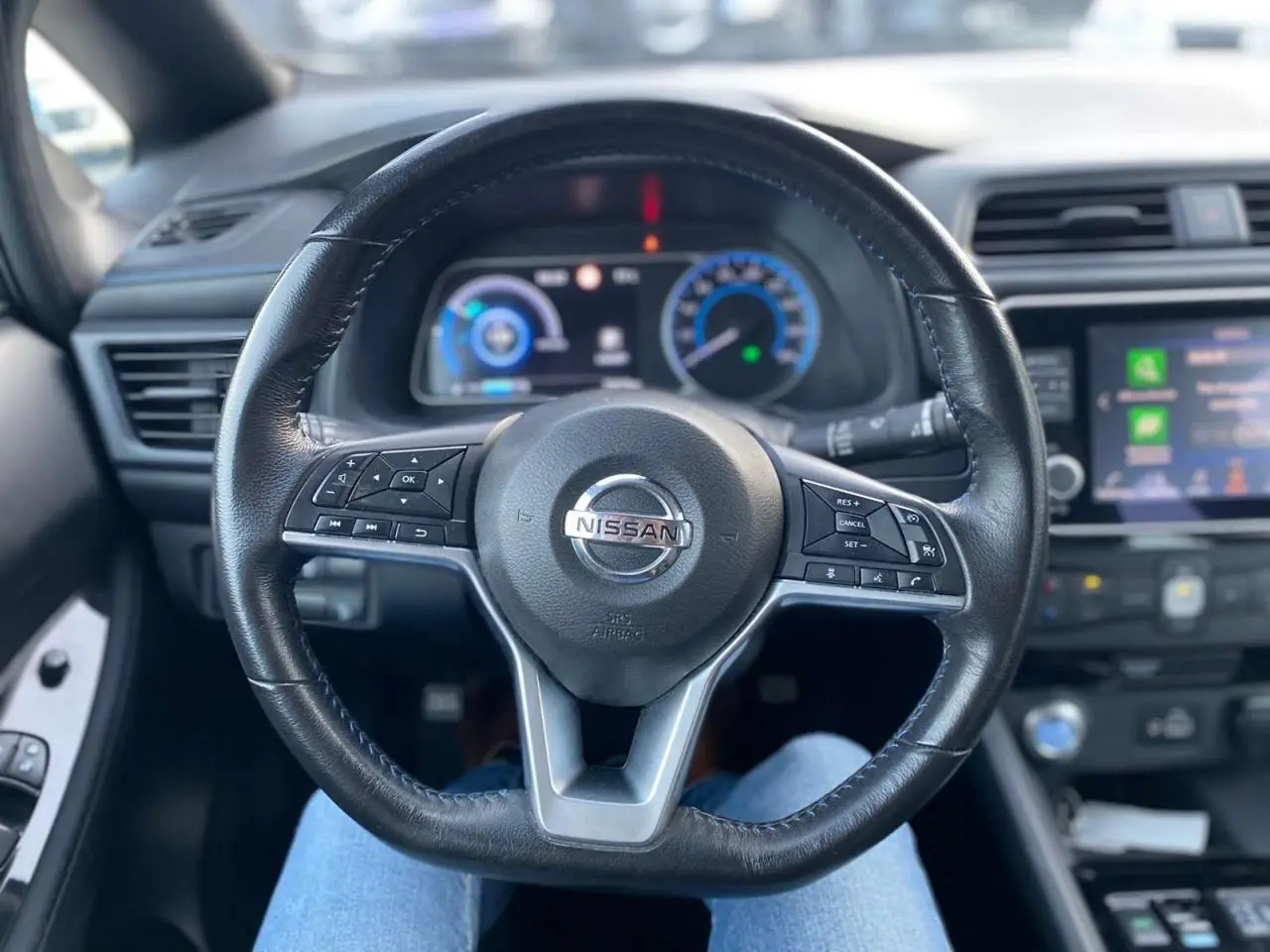Vue centrée sur le volant noir de la Nissan Leaf 40 kWh 2020, avec tableau de bord et écran tactile en arrière-plan.