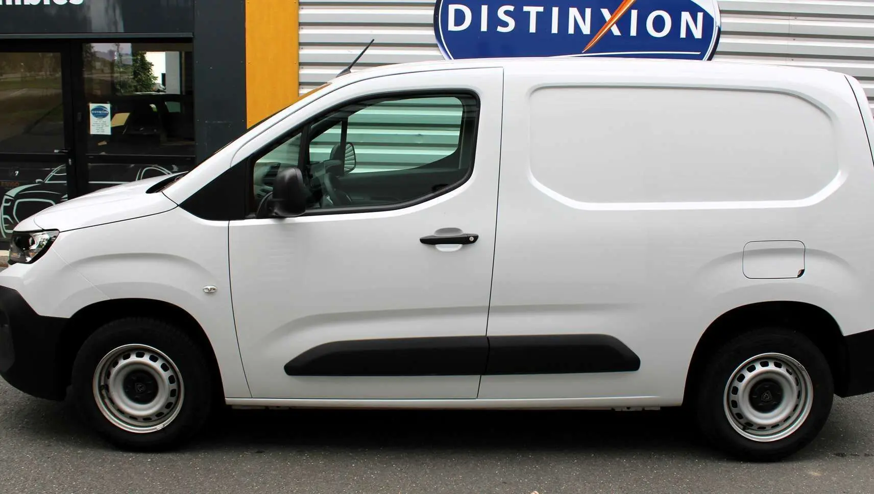 Profil côté gauche du Peugeot Partner Fourgon blanc 2025 avec protections latérales noires et jantes acier simples.