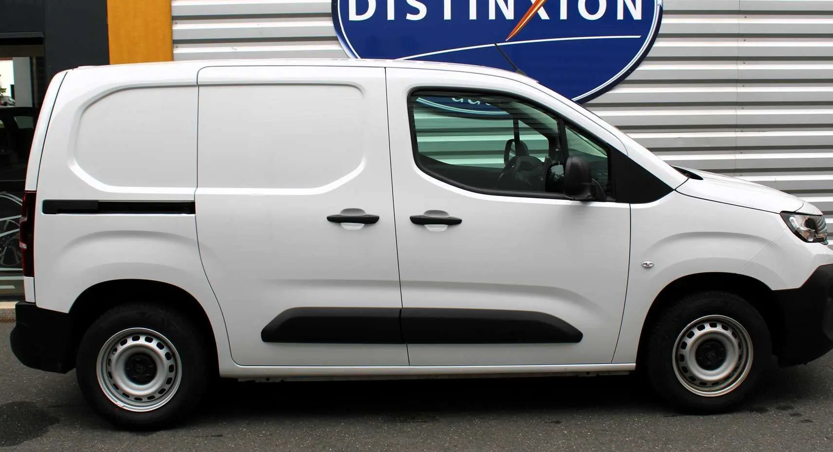 Profil côté gauche du Peugeot Partner Fourgon blanc 2025 avec protections latérales noires et jantes acier.