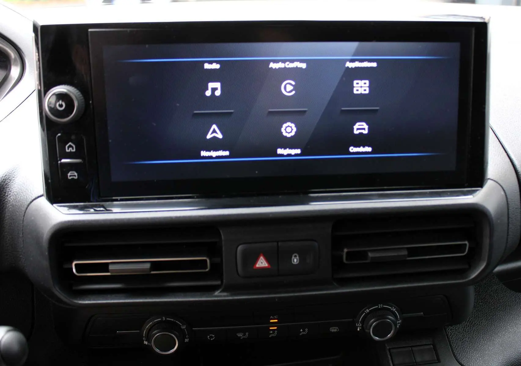 Écran tactile central allumé avec menus radio, navigation et réglages dans l'habitacle du Peugeot Partner Fourgon blanc 2025.