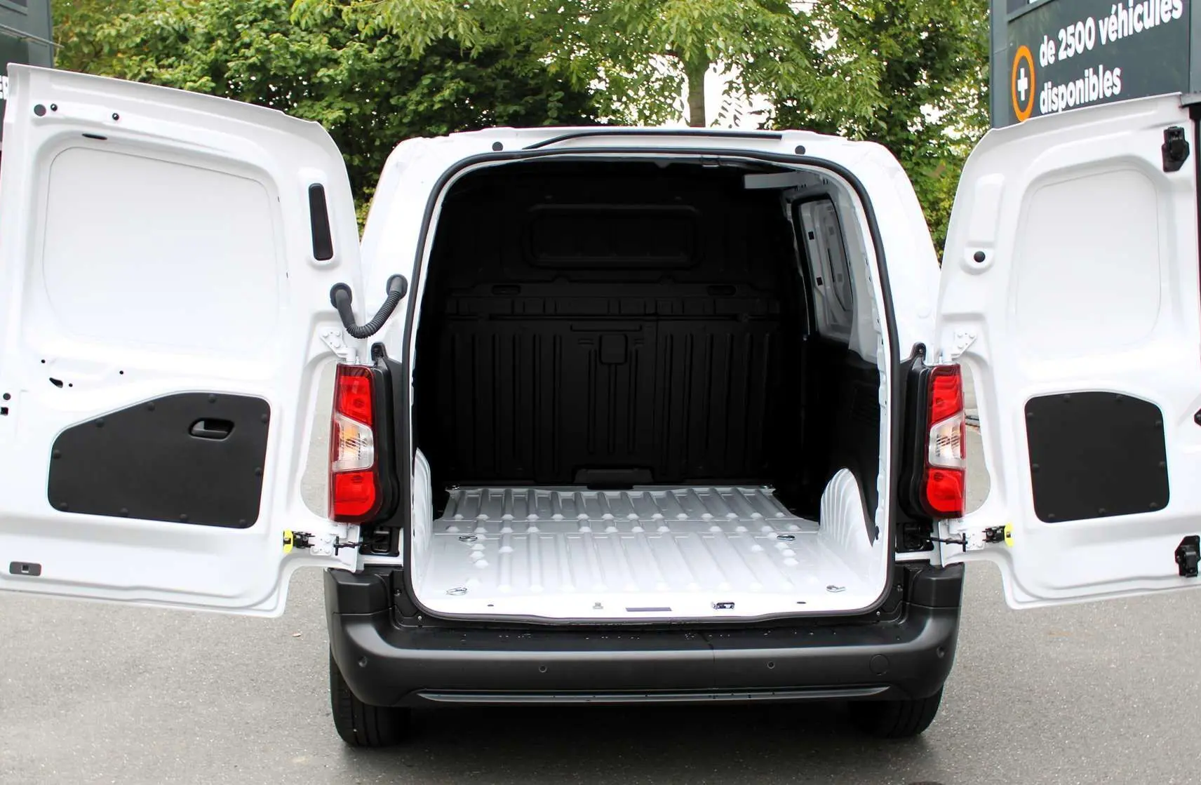 Vue arrière du Peugeot Partner Fourgon blanc 2025 avec portes arrière ouvertes montrant l'espace de chargement vide.