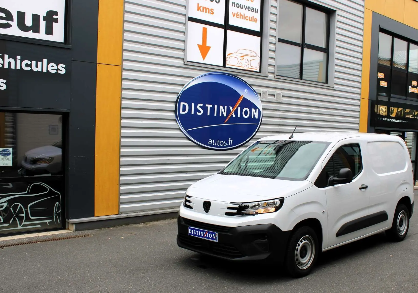 Peugeot Partner Fourgon blanc vu en 3/4 avant droit devant un bâtiment avec logo Distinxion.