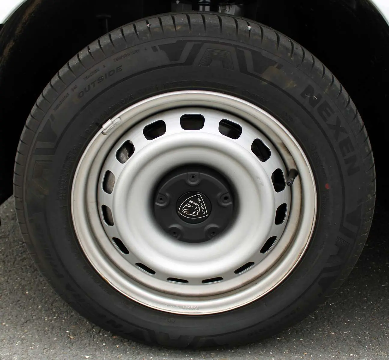 Gros plan sur la roue avant droite du Peugeot Partner Fourgon blanc 2025 avec jante acier et logo Peugeot central.