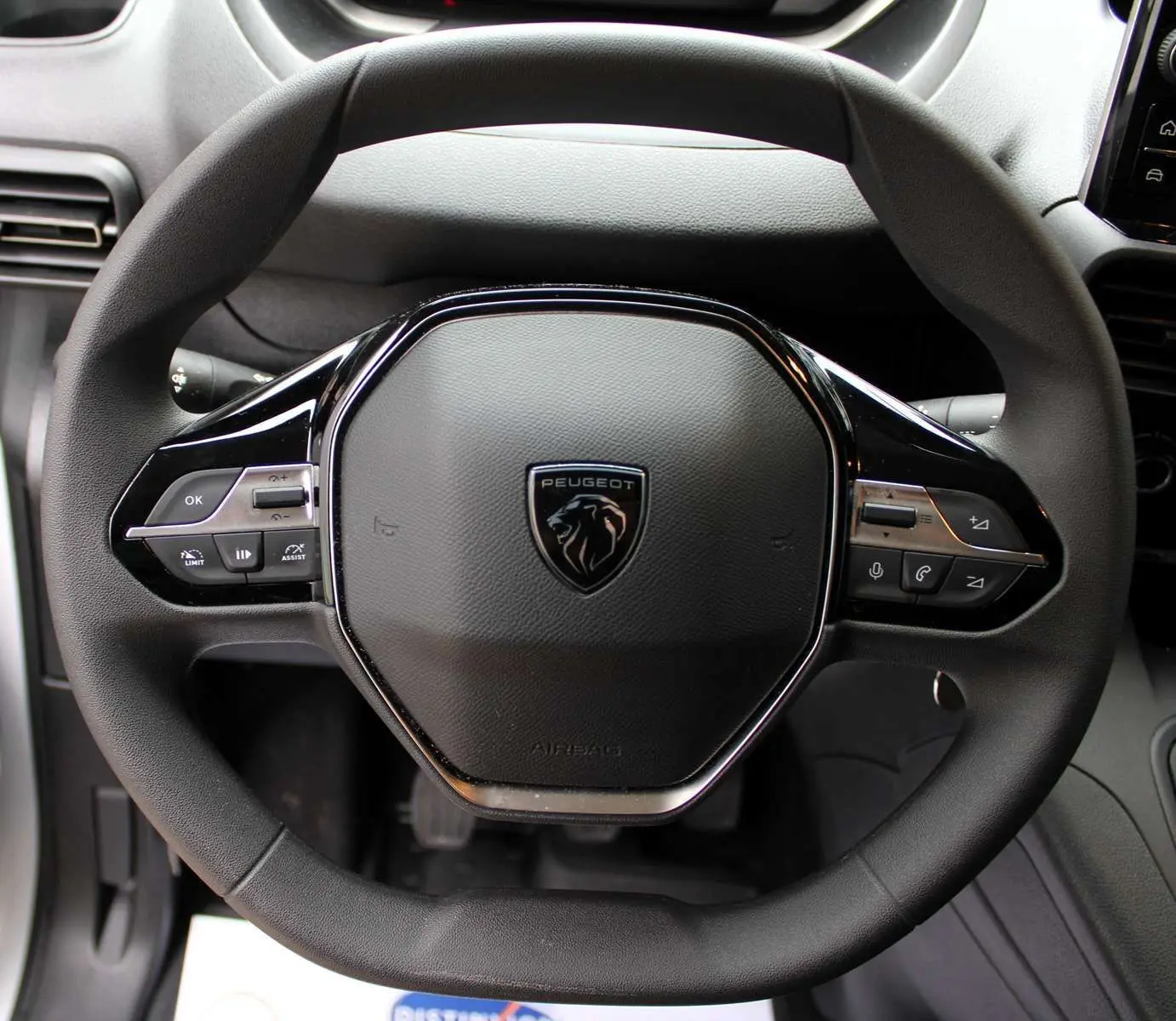 Volant multifonction noir du Peugeot Partner Fourgon 2025 avec commandes intégrées et logo lion central.