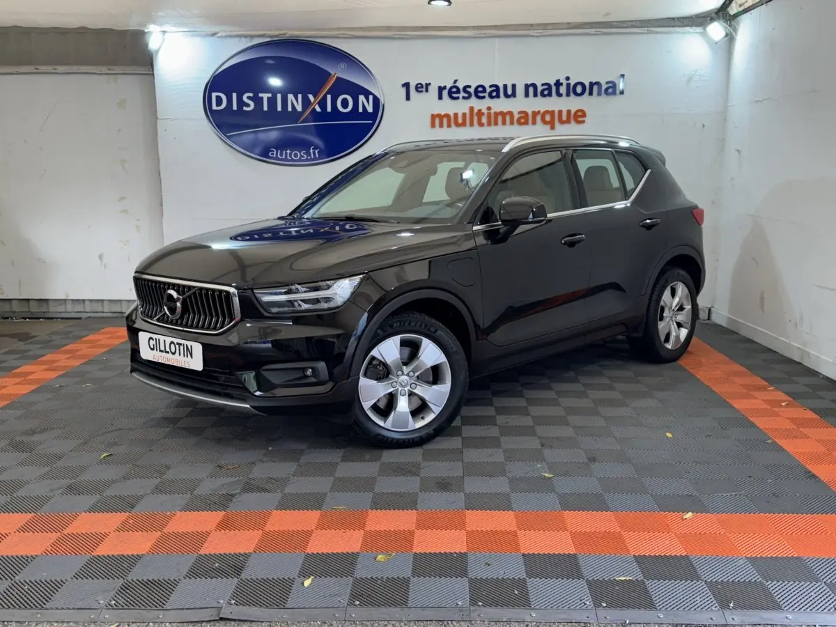 Volvo XC40 Recharge T5 noir en 3/4 avant droit dans un showroom avec sol à damiers gris et orange.