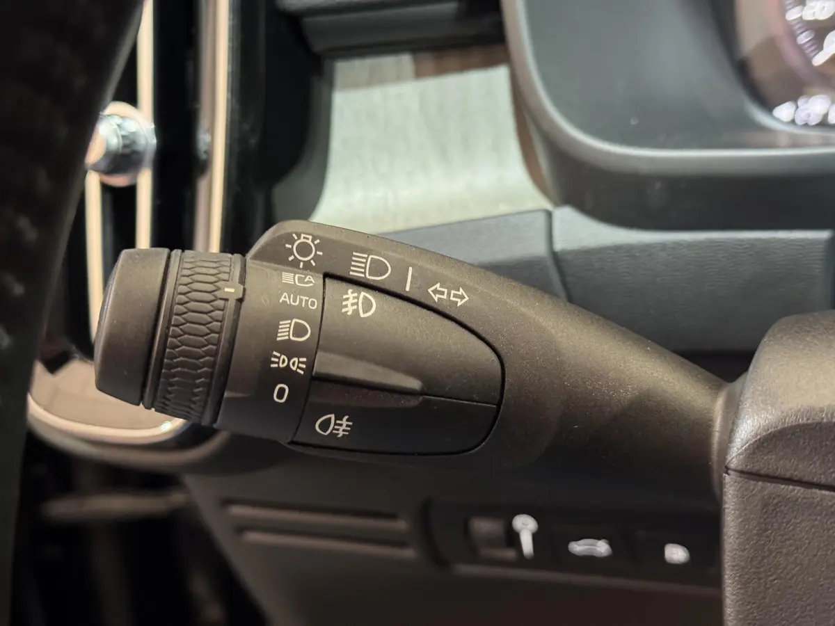 Gros plan sur la commande des phares et clignotants à gauche du volant dans l’habitacle noir du Volvo XC40 Recharge T5 2021.