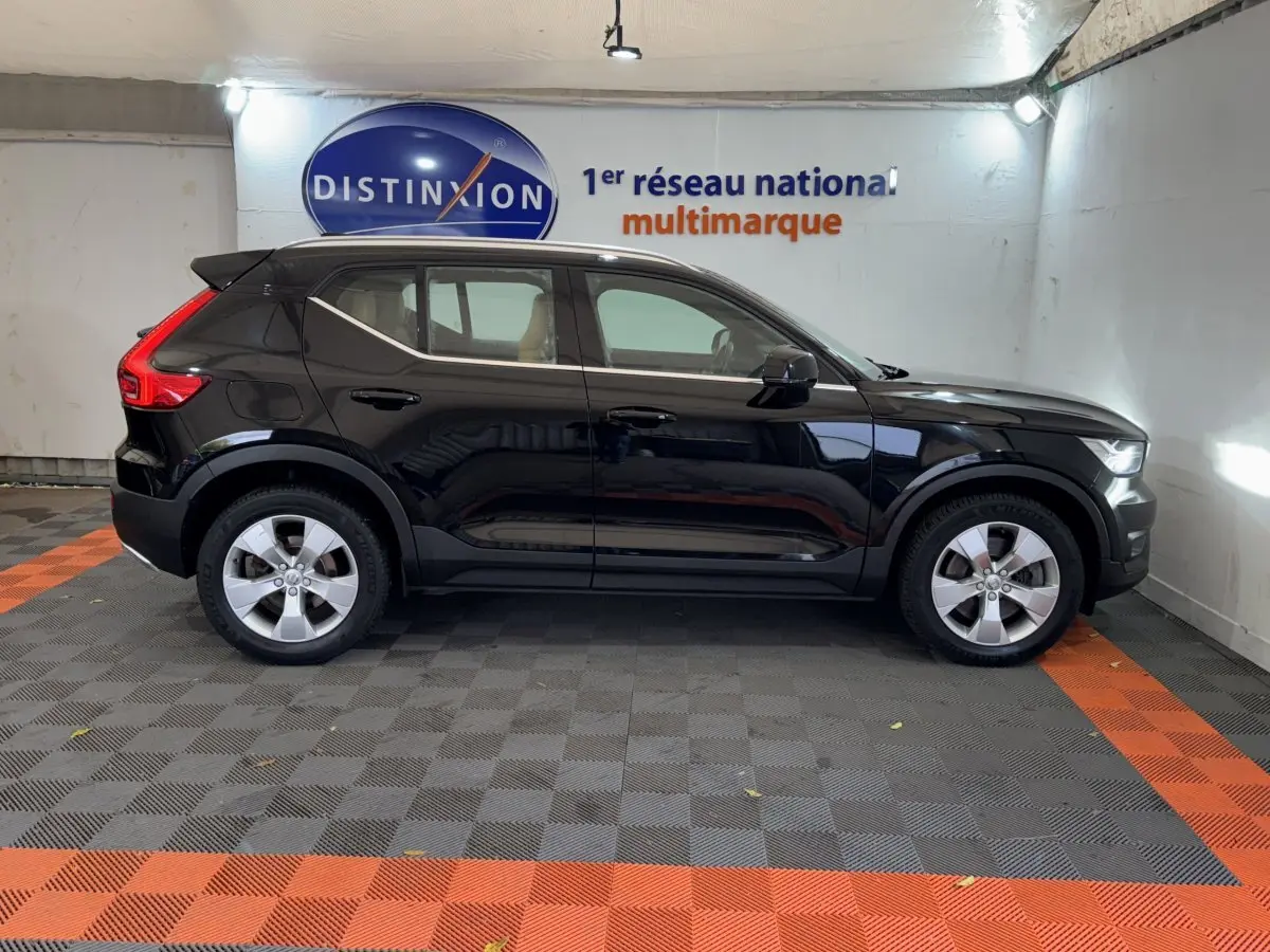 Vue de profil côté gauche d'un Volvo XC40 noir garé en intérieur avec jantes argentées et toit noir contrastant.