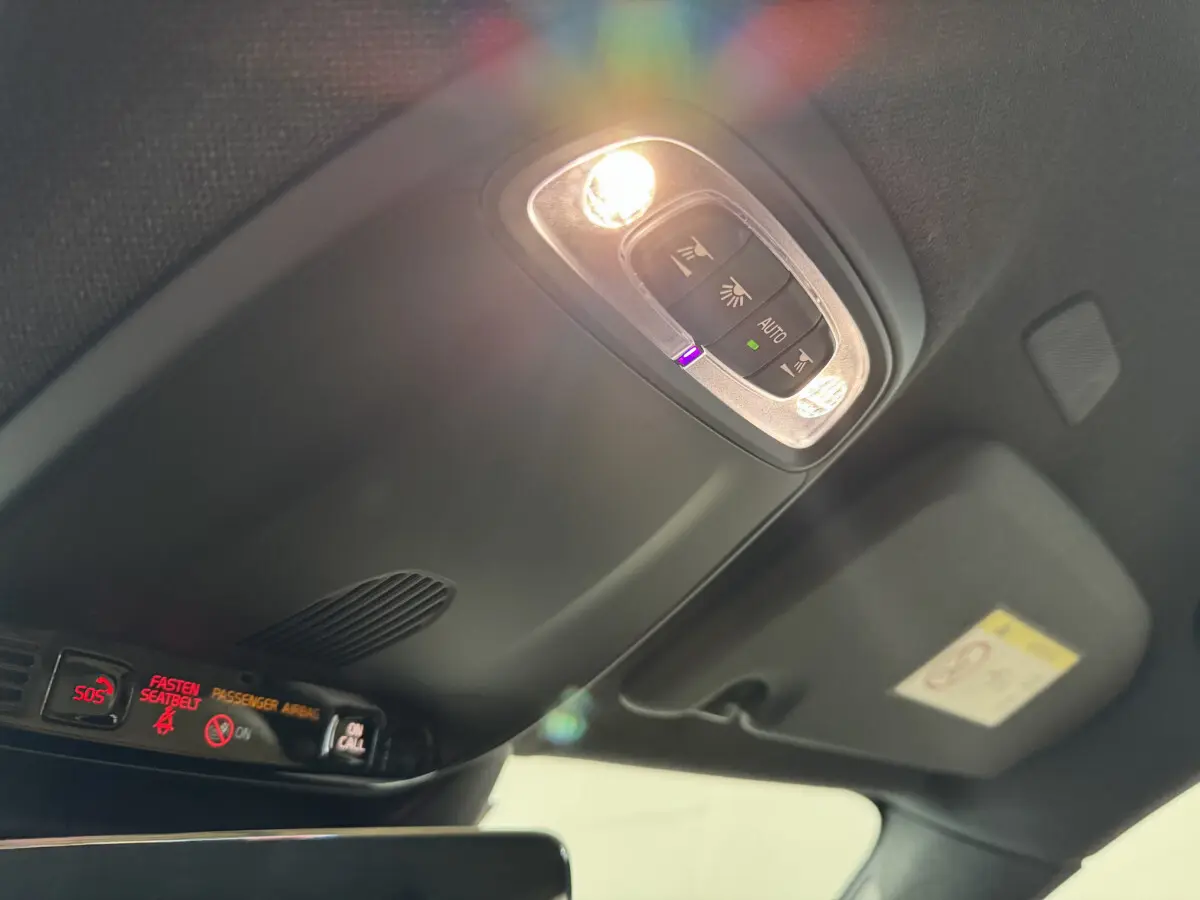Plafonnier intérieur allumé avec commandes et affichages rouges, vue en contre-plongée dans un Volvo XC40 noir.