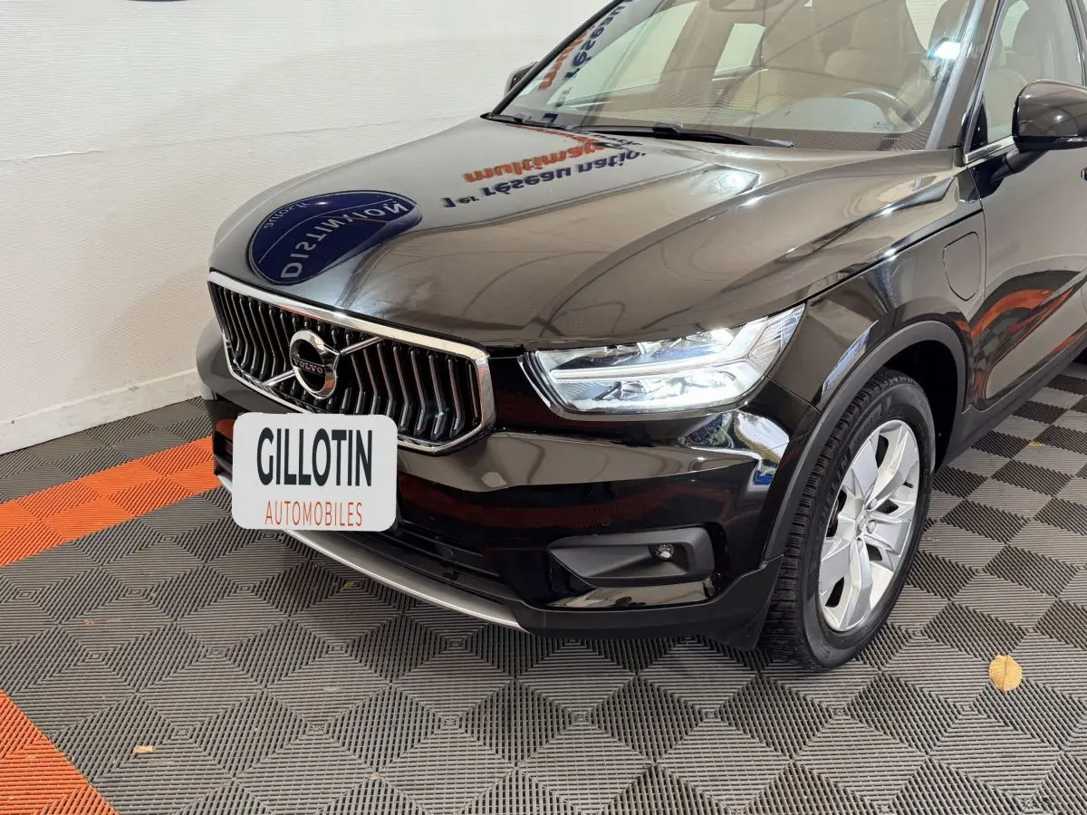 Vue 3/4 avant droit d’un Volvo XC40 Recharge T5 noir, avec calandre chromée et phares LED allumés.
